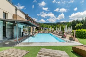 an outdoor swimming pool with chairs and umbrellas at Göbels Schlosshotel "Prinz von Hessen" in Friedewald