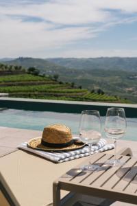 a table with two wine glasses and a hat on it at Casa do Paço Suítes Douro Valley in Peso da Régua +27 photos