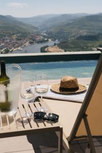 a table with a hat and wine glasses on a balcony at Casa do Paço Suítes Douro Valley in Peso da Régua