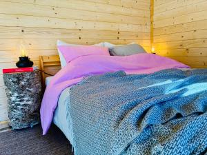 a bedroom with a large bed with a wooden wall at Haapsi Hideaway Garden Cabin in Haapsi