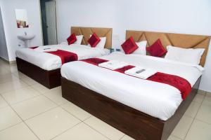 two beds in a hotel room with red and white pillows at Hotel Dream Palace in Mysore