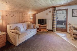 a living room with a white couch and a television at Appartements Alpenrose in Längenfeld