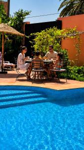 a group of people sitting at a table by a pool at Riad Aïcha Addi Pool & Hammam in Essaouira