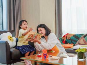a woman and a little girl eating food in a living room at Hyatt Regency Beijing Wangjing in Beijing