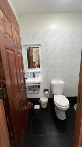 a bathroom with a toilet and a sink and a mirror at Amber Home Ruaka Near Two Rivers Mall & UN in Ruaka
