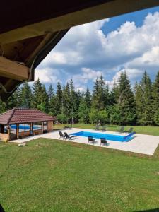 a swimming pool with two chairs and a pavilion at Brvnara Miris Bora - sa bazenom - in Šljivovica