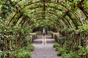 a garden with an archway with plants and a fountain at Fernside Estate and Gardens in Fernside +1 photo