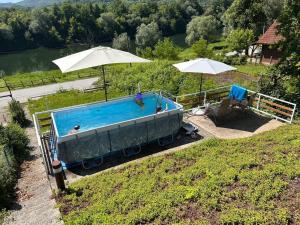 a swimming pool with two umbrellas on a hill at Kuca Suncani brijeg in Pokupsko