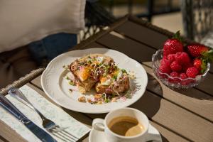 a plate of food with a cup of coffee and strawberries at Kastélykert Vendégház in Bózsva