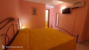 a bedroom with a bed with yellow sheets and a television at Villa Rosaria B&B in Morano Calabro