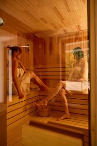 a woman is sitting in a sauna at Kastélykert Vendégház in Bózsva