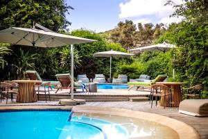 a swimming pool with chairs and umbrellas next to a swimming pool at Thonga Beach Lodge in Mabibi
