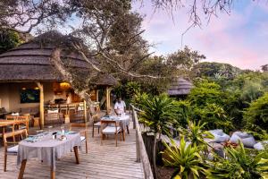 a wooden deck with tables and chairs and a restaurant at Thonga Beach Lodge in Mabibi