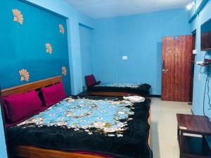 a bedroom with two beds and a blue wall at SB Cottage ooty in Ooty