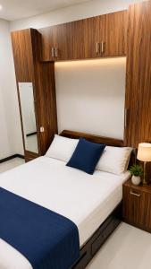 a bedroom with a large white bed with wood paneling at Grand Stay Hotel in Seeduwa