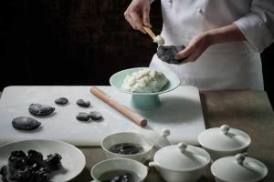 a woman in a kitchen preparing food on a table at Hyatt Regency Beijing Wangjing in Beijing +34 photos
