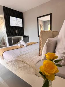 a bedroom with a bed with a vase of yellow flowers at Lamamie Suite Lodge in Thohoyandou