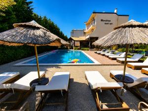 a group of chairs and umbrellas next to a pool at Maritina Apartments in Ixia