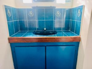 a blue tiled bathroom with a black sink at Gîte Le Tropical in Rodrigues Island