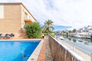 a house with a swimming pool next to a river at Jouvacations Villa 3 Freser con piscina compartida in Empuriabrava