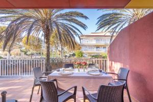 a table and chairs on a patio with palm trees at Jouvacations Villa 3 Freser con piscina compartida in Empuriabrava