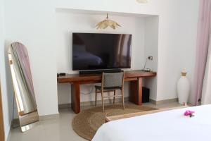 a bedroom with a desk with a television and a chair at La Calma Villa in Gili Islands
