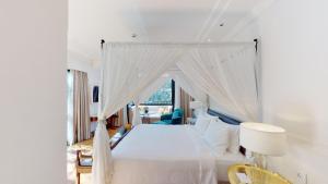 ein weißes Schlafzimmer mit einem Himmelbett mit Fenster in der Unterkunft Radisson Hotel Shimla in Shimla