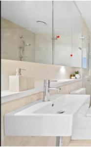 a white bathroom with a sink and a mirror at Olympicpark 12 Free Parking in Sydney