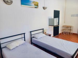 two beds in a room with a tv and a table at Gîte Le Tropical in Rodrigues Island