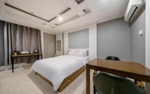 a bedroom with a white bed and a table and chairs at Cats Hotel in Puch'ŏn-yŏk