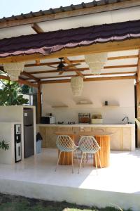 an outdoor kitchen with two chairs and a refrigerator at La Calma Villa in Gili Islands