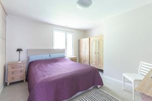 a bedroom with a purple bed and a window at Villa Tuuliniemi in Muurame