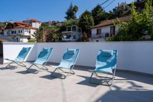 Vier Stühle stehen auf einer Terrasse neben einer weißen Wand in der Unterkunft ERA Suites in Stomio