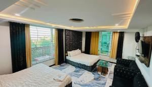 a bedroom with two beds and a tv and a window at Hotel One Ten Mall Road Murree in Murree