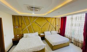 a bedroom with two beds and a wall with red curtains at Hotel One Ten Mall Road Murree in Murree