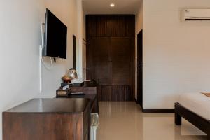 a room with a bed and a desk with a television at Thanawong Pool Villa in Sukhothai