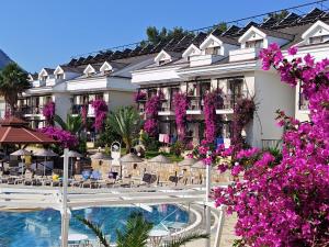 a resort with a swimming pool and purple flowers at Telmessos Neva Hotel - Halal-Non Alcoholic All Inclusive-Muhafazakar Hotel in Oludeniz