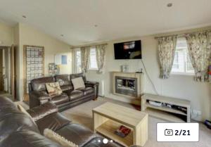a living room with a leather couch and a fireplace at 36 Ravens Nest large 3 bedroom lodge with views No sign written vans allowed on site in High Hesket