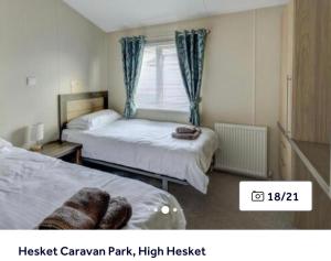 a bedroom with two beds and a window at 36 Ravens Nest large 3 bedroom lodge with views No sign written vans allowed on site in High Hesket