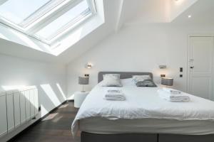 a bedroom with a bed with white sheets and windows at Bed & Breakfast La Linière in Brussels
