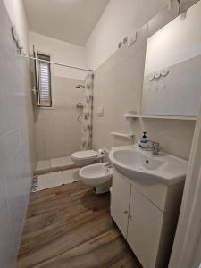a white bathroom with a toilet and a sink at B&B Mare di Ricordi Camera in San Foca