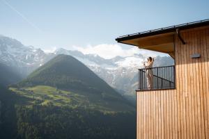 a woman standing on a balcony looking at the mountains at Lahnerhof Chalets - Mountain view and Sauna inclusive in Lutago +33 photos