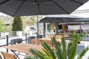 a patio with tables and chairs and umbrellas at Hotel Bürger in Siegen