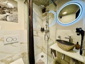 a bathroom with a sink and a glass shower at Peaky Riders Self Check-in Hotel in Zermatt +24 photos