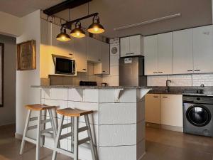 a kitchen with white cabinets and bar stools at Laguna La Crete 33 in Uvongo Beach