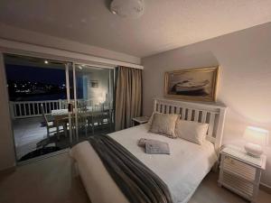 a bedroom with a bed and a balcony with a table at Laguna La Crete 33 in Uvongo Beach +36 photos
