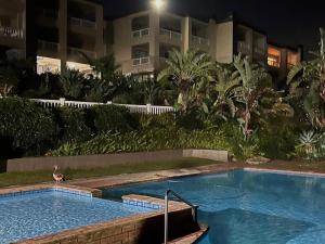 a swimming pool in front of a building at night at Laguna La Crete 33 in Uvongo Beach