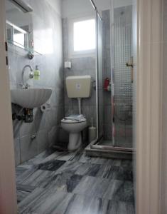 La salle de bains est pourvue de toilettes, d'un lavabo et d'une douche. dans l'établissement Grivas Apartments, à Sivota