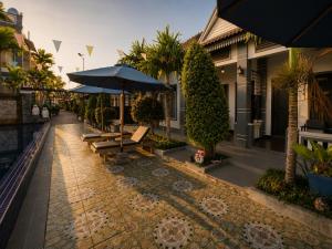 a patio with benches and umbrellas on a street at Champs Elysees Boutique Hotel in Phumĭ Réach Born (2)