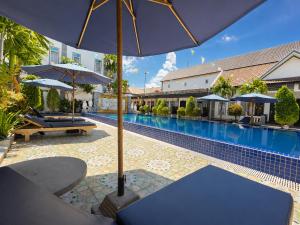 a pool with chairs and umbrellas next to a building at Champs Elysees Boutique Hotel in Phumĭ Réach Born (2)
